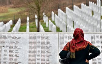 1131699613 A Bosnian Muslim woman, walks by the memorial wall containing the names of the victims at the Srebrenica memorial in Potocari, on March 20, 2019, on the day of the final sentence handed down in the case of Bosnian Serb wartime leader Radovan Karadzic before the Mechanism for International Criminal Tribunals (MTPI) in The Hague. - Former Bosnian Serb leader Radovan Karadzic will spend the rest of his life in jail for the "sheer scale and systematic cruelty" of his crimes in the war that tore his country apart a quarter of a century ago, UN judges said on March 20, 2019. Grim-faced and silent, the 73-year-old stood in the dock as judges in The Hague said they had upheld his 2016 convictions for genocide in the Srebrenica massacre and war crimes throughout the 1990s. (Photo by ELVIS BARUKCIC / AFP) (Photo credit should read ELVIS BARUKCIC/AFP via Getty Images)
