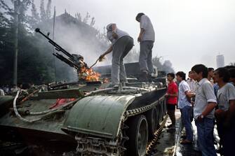 Chinese residents check a burning armoured personnel carrier which was put in on fire by rioters fighting back when the army opened fire on the civilians on June 4, 1989 near Tiananmen Square in Beijing. On the night of 03 and 04 June 1989, Tiananmen Square sheltered the last pro-democracy supporters. A series of pro-democracy protests was sparked by the April 15 death of former communist party leader Hu Yaobang. In a show of force, China leaders vented their fury and frustration on student dissidents and their pro-democracy supporters. Several hundred people have been killed and thousands wounded when soldiers moved on Tiananmen Square during a violent military crackdown ending six weeks of student demonstrations, known as the Beijing Spring movement. According to Amnesty International, five years after the crushing of the Chinese pro-democracy movement, "thousands" of prisoners remained in jail. AFP PHOTO TOMMY CHENG (Photo credit should read TOMMY CHENG/AFP via Getty Images)