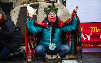 PLYMOUTH, MA - NOVEMBER 26: Chali'Naru Dones, with the United Confederation of Taino People, opens up the 50th Anniversary of The National Day of Mourning with a prayer while kneeling in front of the statue of Wampanoag Sachem Massasoit in Plymouth, MA on Nov. 26, 2020. For the past 50 years Native Americans and supporters gather at noon on Coles Hill overlooking Plymouth Harbor to commemorate a National Day of Mourning on the US thanksgiving holiday.  (Photo by Erin Clark / The Boston Globe via Getty Images)
