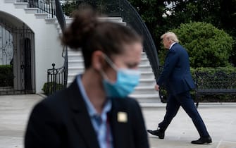 TOPSHOT - US President Donald Trump walks from Marine One to the White House as a secret service agent wearing a face mask looks on May 14, 2020, in Washington, DC. - Trump traveled to Allentown, Pennsylvania to visit a medical supply distributor Owens and Minor Inc. (Photo by Brendan Smialowski / AFP) (Photo by BRENDAN SMIALOWSKI/AFP via Getty Images)