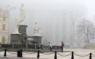A woman takes a photo of a Monument to Princess Olga, Apostle Andrew, Cyril and Methodius on a foggy Sunday in downtown of Kyiv, Ukraine on 12 December 2021. (Photo by STR/NurPhoto via Getty Images)
