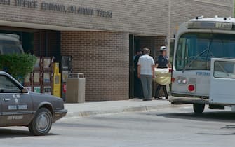 (Original Caption) Edmund, Oklahoma: Police officers carry one of 14 bodies out of the Edmund Post Office 8/20 where a disgruntled postal worker, Pat Sherrill, shot and killed 14 persons early in the day, then killed himself.