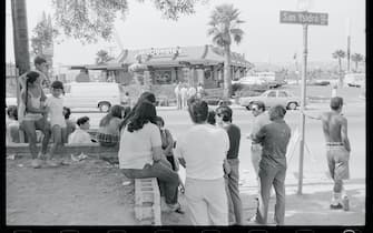 A crowd of people watches the scene outside the McDonald's restaurant in which a lone gunman killed 20 people in San Ysidro, California.