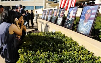 epa01928504 The family of Army specialist Kham S. Xiong grieves by his photo at the memorial service for the 12 soldiers and one civilian killed at Fort Hood U.S Army Post near Killeen, Texas, USA 10 November 2009. Army Major Malik Nadal Hasan reportedly shot and killed 13 people, 12 soldiers and one civilian, and wounded 30 others in a rampage 05 November at the base's Soldier Readiness Center where deploying and returning soldiers undergo medical screenings.  EPA/TANNEN MAURY