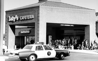 Overall view of city police car parked nr.the front entrance to Luby's Cafeteria w. wreaths & baskets of flowers placed there by mourners for the 23 killed & the 27 others wounded in a massacre by crazed gunman George Hennard who used two 9-mm semi-autom.atic pistols    (Photo by Mark Perlstein/Getty Images)