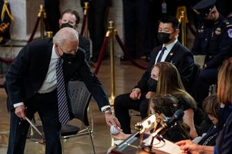 WASHINGTON, DC - APRIL 13: US President Joe Biden hands a Capitol doom shaped toy that belongs to U.S Capitol Police officer William Evans daughter, Abigail, to her during a lying in honor ceremony of U.S. Capitol Police officer William Evans in the U.S. Capitol rotunda on April 13, 2021 in Washington, DC. Officer Evans, who was killed in the line of duty during the attack outside the U.S. Capitol on April 2, will lie in honor in the Capitol rotunda today. (Photo by Amr Alfiky-Pool/Getty Images)