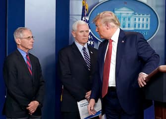 U.S. President Donald Trump, right, speaks to Vice President Mike Pence, center, and Anthony Fauci, director of the National Institute of Allergy and Infectious Diseases, during a news conference in the Brady Press Briefing Room at the White House in Washington, D.C., U.S., on Wednesday, March 25, 2020. The Trump administration is expected to soon direct how manufacturers will distribute crucial medical supplies -- including protective gear and ventilators -- to combat the coronavirus outbreak, alleviating what U.S. governors have complained is a chaotic marketplace for the products. Photographer: Sarah Silbiger/UPI/Bloomberg via Getty Images