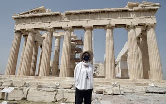 ATHENS, GREECE - MAY 18: A Culture ministry employee wearing a face mask stands in front of the Parthenon temple as the Acropolis archaeological site opens to visitors on May 18, 2020 in Athens, Greece. Greece reopened all open-air archaeological sites to the public after a two-month closure due to the coronavirus (COVID-19) pandemic. (Photo by Milos Bicanski/Getty Images)