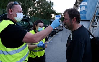 A security staff member wearing a protective mask checks the temperature of a photo-reporter before the football match between FC Lokomotiva and FC Osijek at the Kranjceviceva stadium in  Zagreb on June 7, 2020, as Croatia's first and second division resumed this weekend behind closed doors, with the easing of lockdown measures taken to curb the spread of the COVID-19 pandemic, caused by the novel coronavirus. (Photo by Denis LOVROVIC / AFP) (Photo by DENIS LOVROVIC/AFP via Getty Images)