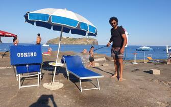 Sanificazione lettini da mare alla scoglera del faro a Ventotene Un addetto alla manutenzione della spiaggia durante la sanificazione dei lettini alla scoglera del faro a Ventotene, 25 giugno 2020.
ANSA/ Lara Gallina