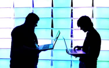 HAMBURG, GERMANY - DECEMBER 28:  Participant hold their laptops in front of an illuminated wall at the annual Chaos Computer Club (CCC) computer hackers' congress, called 29C3, on December 28, 2012 in Hamburg, Germany. The 29th Chaos Communication Congress (29C3) attracts hundreds of participants worldwide annually to engage in workshops and lectures discussing the role of technology in society and its future. (Photo by Patrick Lux/Getty Images)