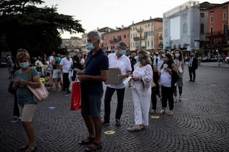 Guests wearing face masks wait as they arrive before a concert at the Arena in Verona, northern Italy, on July 25, 2020. - This is the first show with new dispositions against the spread of the novel coronavirus (Covid-19) during this season. (Photo by MARCO BERTORELLO / AFP) (Photo by MARCO BERTORELLO/AFP via Getty Images)
