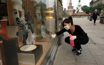 Una commessa pulisce e sanifica  il suo negozio in vista della riapertura del 18 maggio in Via Dante, Milano, 14 maggio 2020, Ansa / Paolo Salmoirago