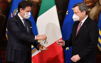 epa09009077 Italy's new Prime Minister Mario Draghi (R) receives a small bell by outgoing prime minister Giuseppe Conte (L) to mark the government handover and to open the first Council of Ministers at Chigi Palace in Rome, Italy, 13 February 2021. Former European Central Bank (ECB) chief Mario Draghi has been sworn in on the day as Italy's prime minister after he put together a government securing broad support across political parties following the previous coalition's collapse.  EPA/ETTORE FERRARI / POOL
