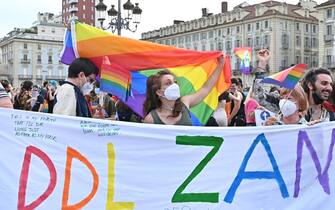 Giovani in piazza con bandiere arcobaleno e striscioni