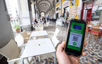 Green pass sullo schermo di uno smartphone mostrato nei pressi di un ristorante, a Roma