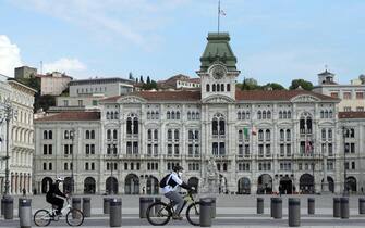 ITALY PANDEMIC CORONAVIRUS COVID19 epa08387064 A handout photo made available by the Regione Friuli Press Office shows shows a father with son wearing face masks enjoing a bicycle ride in front of the Palazzo del Municipio (city hall) in Trieste, northeast Italy, 27 April 2020, during the coronavirus disease (COVID-19) pandemic. EPA/GIOVANNI MONTENERO/REGIONE CRONACHE AGENCY/REGIONE FVG HANDOUT HANDOUT EDITORIAL USE ONLY/NO SALES