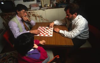 Renzo Bossi osserva suo padre Umberto (s) e Roberto Maroni mentre giocano a dama nella casa di Gemonio a meta' anni novanta. ANSA / MAURO VALLINOTTO