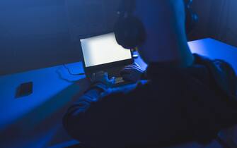 hacker with coding on laptop computer in dark room