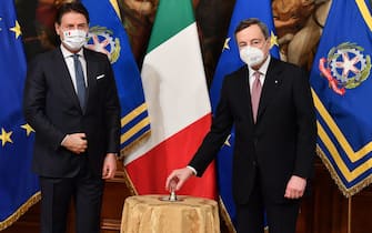 epa09009159 Italy's new Prime Minister Mario Draghi (R) receives a small bell by outgoing prime minister Giuseppe Conte to mark the government handover and to open the first council of Ministers at Chigi Palace in Rome, Italy, 13 February 2021. Former European Central Bank (ECB) chief Mario Draghi has been sworn in on the day as Italy's prime minister after he put together a government securing broad support across political parties following the previous coalition's collapse.  EPA/ETTORE FERRARI / POOL