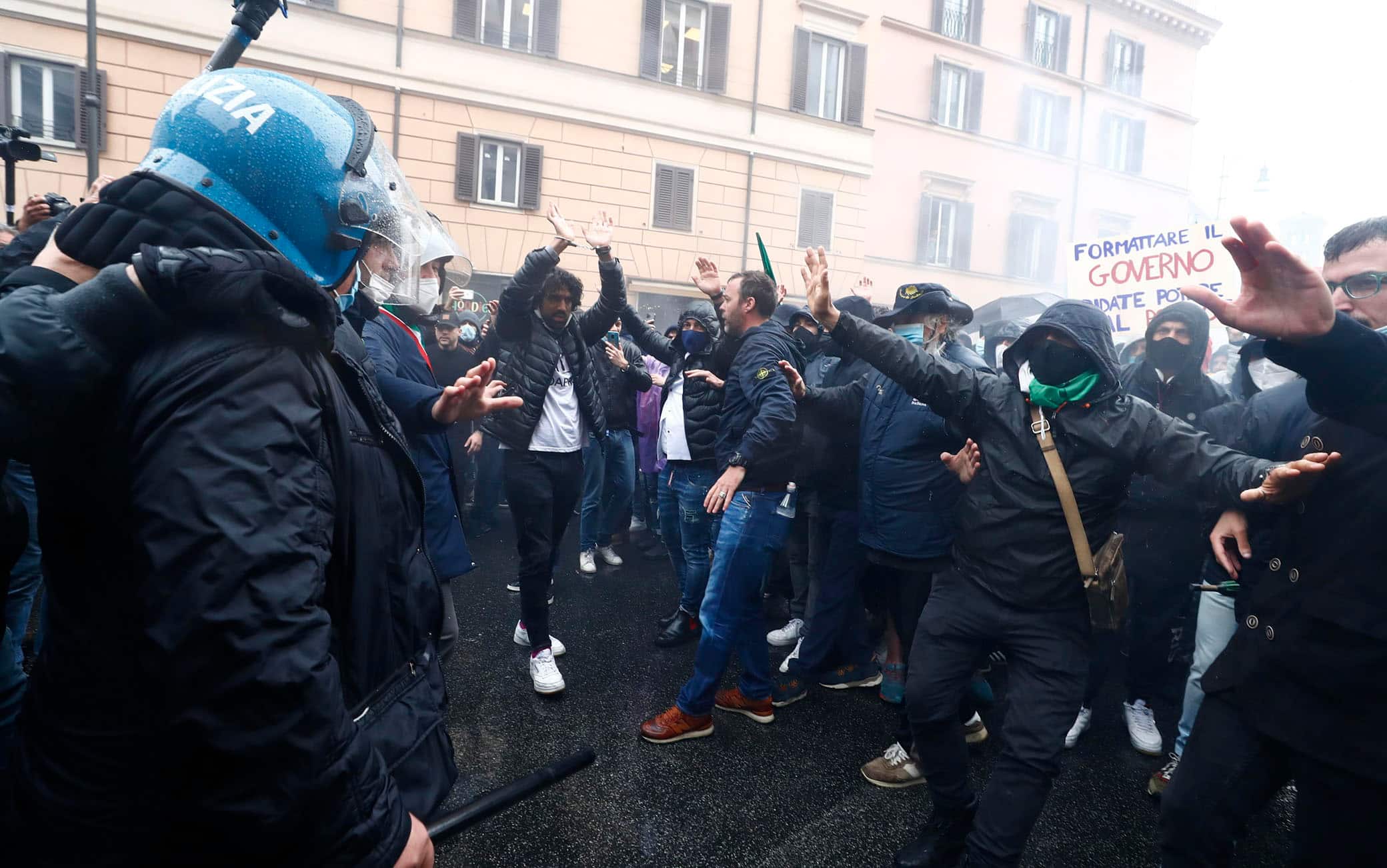 Alcuni partecipanti alla manifestazione organizzata a Piazza San Silvestro dal movmento IoApro si confrontano con le forze dell'ordine schierate in tenuta antisommossa, Roma, 12 aprile 2021.   I manifestanti, alcuni con le manette, e le mani alzate chiedono di andare verso Montecitorio. ANSA/ANGELO CARCONI