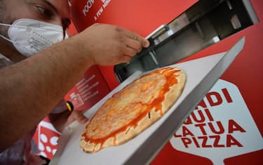 Un ragazzo preleva una pizza da un distributore automatico di pizza a Roma, 9 giugno 2021. ANSA/CLAUDIO PERI