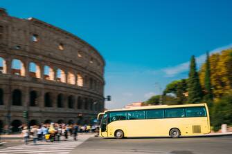 Rome, Italy. Colosseum. Yellow Bus Moving On Street Near Flavian Amphitheatre. Famous World UNESCO Landmark.