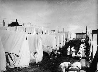 Nurses care for victims of a Spanish influenza epidemic outdoors amidst canvas tents during an outdoor fresh air cure, Lawrence, Massachusetts, 1918 (Photo by Hulton Archive/Getty Images)