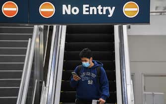 SYDNEY, AUSTRALIA - JULY 07: A man wearing a face mask looks at his phone as he arrives at Sydney Airport on one of the last flights out of Melbourne to Sydney on July 07, 2020 in Sydney, Australia. The NSW-Victoria border will close at 11:59pm on Tuesday evening due to a large spike in COVID-19 cases in Victoria. It is the first time in 100 years the border between the two states has been closed, and comes after Victoria recorded its highest-ever daily increase in cases, 127, since the start of the pandemic on Monday, along with the deaths of two Victorian men. From 12:01 Wednesday 8 July, NSW residents returning from Victoria will need to self isolate for 14 days. Special provisions will be in place for border communities such as Albury-Wodonga as well as freight operations and other critical services. (Photo by James D. Morgan/Getty Images)