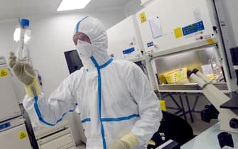 French engineer-virologist Thomas Mollet looks at a 40ml flask infected with a Sars-CoV-2 virus at the Biosafety level 3 laboratory (BSL3) of the Valneva SE Group headquarters in Saint-Herblain, near Nantes, western France, on July 30, 2020. - Could the Covid-19 vaccine be found by a biotechnology company in western France, far from major global research centers? The hypothesis is more than plausible for the British government, which has just signed an important agreement with it. (Photo by JEAN-FRANCOIS MONIER / AFP) (Photo by JEAN-FRANCOIS MONIER/AFP via Getty Images)