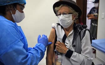 A medical worker applies a flu vaccine to an elderly woman in Asuncion, on, April 15, 2020 during the coronavirus COVID-19 pandemic. - Health authorities in Paraguay are encouraging people over 60 to be vaccinated against the flu, also a respiratory disease, to reduce complications of those who might contact the new coronavirus. (Photo by Norberto DUARTE / AFP) (Photo by NORBERTO DUARTE/AFP via Getty Images)