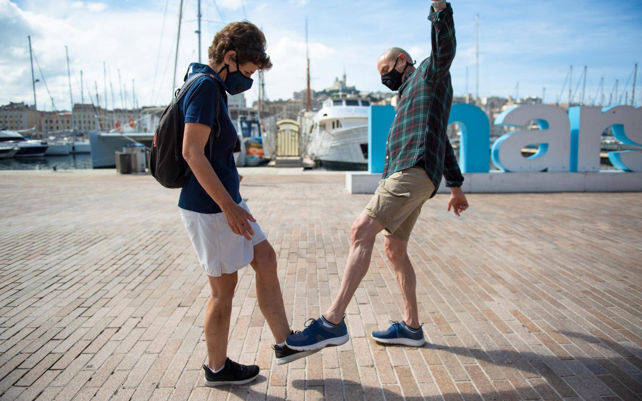 A man and a woman pose as they greet each other with their feet in the Vieux Port of Marseille southern France, on May 17, 2020, in order to use new social distanciation gesture to salute people as a prophylactic measure against the spread of the Covid-19 disease caused by the novel coronavirus. (Photo by CLEMENT MAHOUDEAU / AFP) (Photo by CLEMENT MAHOUDEAU/AFP via Getty Images)