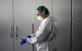 A nurse puts on her Personal Protective Equipment (PPE) before starting to work on the preparation of the Intensive care unit in the new Covid-19 Hospital on March 29, 2020 in Verduno, near Alba, Northwestern Italy on the eve of its official opening, as part of the measures taken to fight against the spread of the novel coronavirus. - The hospital have seven beds of intensive care and fifty beds for patients infected by the COVID-19. (Photo by MARCO BERTORELLO / AFP)