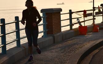 Un runner sulle strade deserte a Genova dopo il rafforzamento delle misure del Governo per contenere il contaggio da Covid-19. Genova, 21 Marzo 2020
ANSA/LUCA ZENNARO

