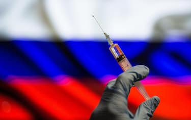 In this photo illustration a close up of a hand holding a medical syringe in front of the Russian Flag. (Photo by Thiago Prudêncio / SOPA Images/Sipa USA)