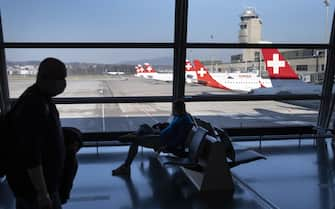 epa09091914 Passengers wearing face masks wait before boarding in an airplane in front of parked Swiss International Air Lines airplanes at the Zuerich Airport (Flughafen Zuerich) amid the coronavirus disease (COVID-19) outbreak, in Kloten, Switzerland, 23 March 2021. Switzerland as many countries in Europe impose coronavirus restrictions to fight against the spread of coronavirus COVID-19.  EPA/LAURENT GILLIERON