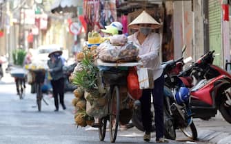 epa09236383 A street vendor wearing a face mask pushes her bicycle in Hanoi, Vietnam, 30 May 2021. Vietnam has recently detected a new coronavirus variant which combines the Indian and UK COVID-19 variants, according to Vietnamese Health Minister Nguyen Thanh Long.  EPA/LUONG THAI LINH