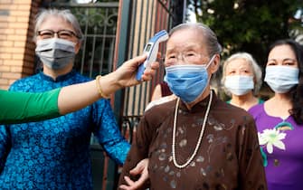epa09221957 Doan Thi Thuan, 96,  has her temperature measured before entering a polling station on election day in Hanoi, Vietnam 23 May 2021. Vietnam holds elections to elect members of the 15th National Assembly and the People's Councils at all levels for the 2021-2026 tenure on 23 May 2021, amid the coronavirus disease (COVID)-19 pandemic.  EPA/LUONG THAI LINH