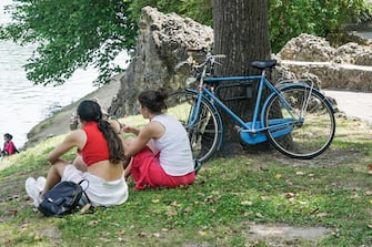 Due ragazze cercano sollievo dal caldo afoso riposandosi sotto un albero ai giardini del parco del Valentino in riva al fiume Po, Torino, 18 giugno 2021. ANSA/TINO ROMANO