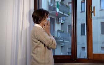 Italia , Milano - anziana signora con mascherina triste e in solitudine  a casa durante Covid-19 Coronavirus lockdown epidemia - vita quotidiana in appartamento