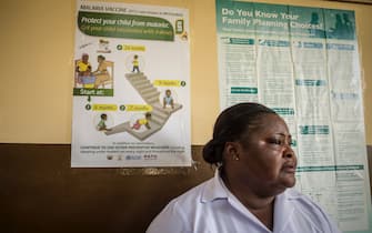 A nurse stands in front of a Malaria vaccine poster at Ewim Polyclinic in Cape Coast, Ghana, on April 29, 2019. - Ewim Polyclinic on April 30, 2019 was the first in Ghana to roll out the Malaria vaccine Mosquirix. After Malawi, Ghana is the second country to launch the vaccine. Known by its lab initials as RTS,S but branded Mosquirix, the vaccine has passed lengthy scientific trials, which found it to be safe and reduced the risk of Malaria by nearly 40 percent -- the best-ever recorded. It was approved by European regulators in 2015. (Photo by CRISTINA ALDEHUELA / AFP) (Photo by CRISTINA ALDEHUELA/AFP via Getty Images)