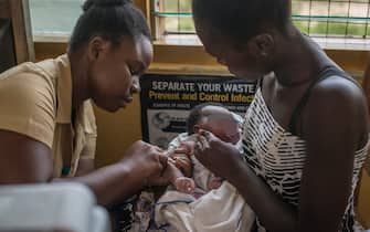 A nurse administers a vaccine to a child at Ewin Polyclinic in Cape Coast on April 30, 2019. - Ewim Polyclinic was the first in Ghana to roll out the Malaria vaccine Mosquirix. After Malawi, Ghana is the second country to launch the vaccine. Known by its lab initials as RTS,S but branded Mosquirix, the vaccine has passed lengthy scientific trials, which found it to be safe and reduced the risk of Malaria by nearly 40 percent. (Photo by CRISTINA ALDEHUELA / AFP)        (Photo credit should read CRISTINA ALDEHUELA/AFP via Getty Images)