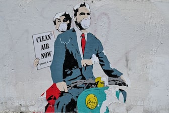 TOPSHOT - A mural by street artist "TV Boy" depicting a famous film "Roman Holiday" with Gregory Peck and Audrey Hepburn as she  holding a banner reading "Clear Air Now" is displayed on a wall near ancient Colosseum, in central Rome on March 14, 2020, during the COVID-19 outbreak caused by the novel coronavirus. (Photo by Andreas SOLARO / AFP) (Photo by ANDREAS SOLARO/AFP via Getty Images)