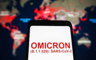 UKRAINE - 2021/11/26: In this photo illustration, words that say Omicron (B.1.1.529): SARS-CoV-2 is seen on a mobile phone screen in front of the COVID-19 Map of Johns Hopkins Coronavirus Resource Center in the background. (Photo Illustration by Pavlo Gonchar/SOPA Images/LightRocket via Getty Images)