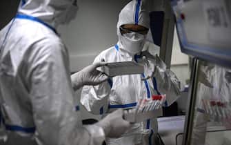 Laboratory technicians wearing protective equipment work on the genome sequencing of the SARS-CoV-2 virus (Covid-19) and its variants at the Centre National de Reference (CNR - National Reference Centre) of respiratory infections viruses of the Pasteur Institute in Paris on January 21, 2021. (Photo by Christophe ARCHAMBAULT / AFP) (Photo by CHRISTOPHE ARCHAMBAULT/AFP via Getty Images)