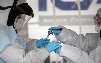 STAMFORD, CT - MARCH 23: Health workers dressed in personal protective equipment (PPE) handle a coronavirus test at a drive-thru testing station at Cummings Park on March 23, 2020 in Stamford, Connecticut. Availability of protective clothing for medical workers has become a major issue as COVID-19 cases surge throughout the United States. The Stamford site is run by Murphy Medical Associates. (Photo by John Moore/Getty Images)