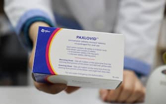 epa09775282 A pharmacist displays a case of Paxlovid, a COVID-19 treatment pills developed by Pfizer Inc., at a drugstore in Seoul, South Korea, 21 February 2022. The age restriction on the administration of the pills to those with underlying diseases was lowered to 40 from 50.  EPA/YONHAP SOUTH KOREA OUT
