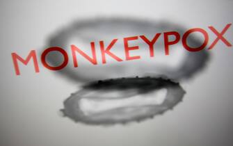 1240918714 'Monkeypox' sign and monkeypox illustrative models displayed on a screen are seen in this multiple exposure illustration photo taken in Krakow, Poland on May 26, 2022. (Photo by Jakub Porzycki/NurPhoto)