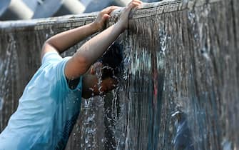 A boy cools off in a fountain during a hot summer day in downtown Moscow on July 13, 2021. - Russia's meteorological service said on July 13, 2021 the country could see its hottest summer on record, driven by climate change, after a record-breaking heatwave in June. Moscow was hit by a historic heat wave at the end of June, with temperatures reaching a 120-year record. (Photo by Kirill KUDRYAVTSEV / AFP) (Photo by KIRILL KUDRYAVTSEV/AFP via Getty Images)