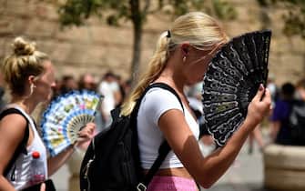 TOPSHOT - Two women use fans to fight the scorching heat during a heatwave in Seville on June 13, 2022. - Spain was today already in the grips of a heatwave expected to reach "extreme" levels, and France is bracing for one, too, as meteorologists blame the unusually high seasonal temperatures on global warming. (Photo by CRISTINA QUICLER / AFP) (Photo by CRISTINA QUICLER/AFP via Getty Images)